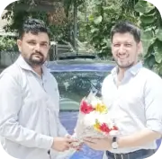 Pair holding flowers near car in parking area, signifies special occasion and automotive lifestyle.